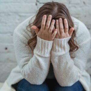 faceless woman covering face with hands while sitting at home