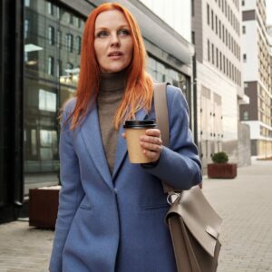 a woman walking while holding a cup of coffee