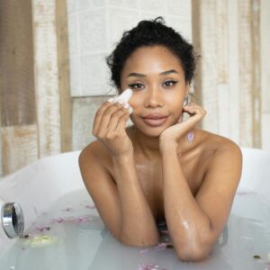 sensual black woman doing massage of face in bathtub