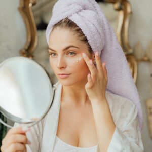 woman looking in the mirror and applying a face cream