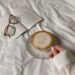 hand of a person holding a cup of coffee near and open book