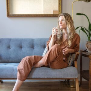 a woman sitting comfortably on the couch while holding a mug