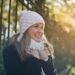 photography of woman in black jacket and white knit cap smiling next to black metal fence